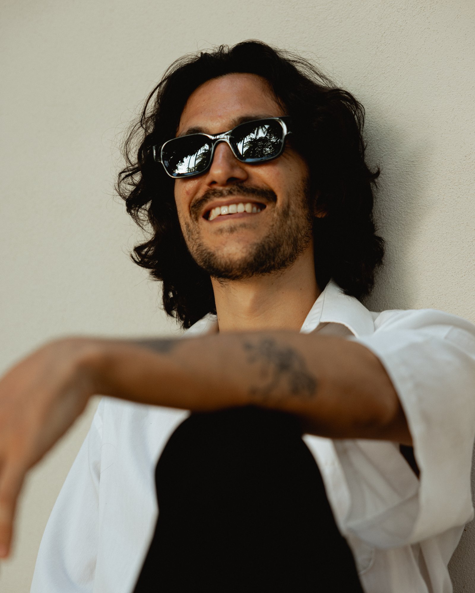 Portrait of the RELAT founder, smiling, leaning against a sunlit wall